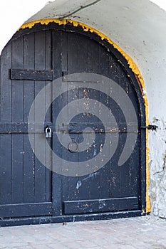 Medieval black door with metal in white wall of church