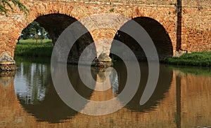 medieval bridge made of red brick on the river