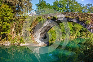 Medieval bridge with moss over the river in France. Old roman bridge in forest. Medieval architecture. Vintage arch bridge.