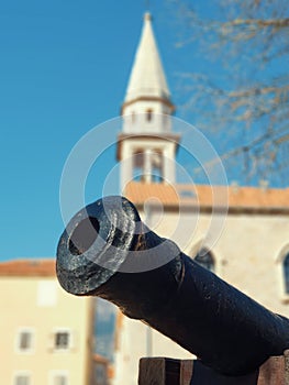 Medieval cannon in front of blurred Tower of St. John the Baptist Cathedral .in Budva in Montenegro