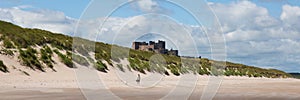 Medieval castle by a beach Bamburgh Northumberland north England UK with white sand panoramic view