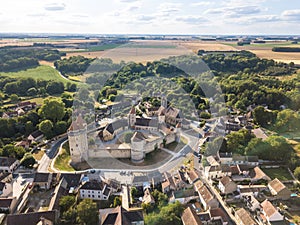 Medieval castle with fortified walls, towers and donjon in rural village in France, aerial view from drone of renovated fortress