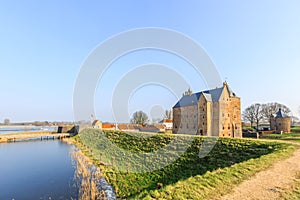 Medieval castle Slot Loevestein by earthen wall and moat at River Waal