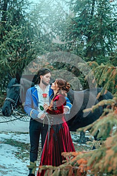 Medieval couple in love man and woman hugging in winter forest. Vintage clothing red long dress. Blue costume tailcoat