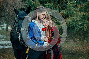 Medieval couple in love man and woman hugging in winter forest. Vintage clothing red long dress. Blue costume tailcoat