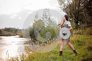 Medieval fantasy female warrior with war paint on her face, in chain mail armor, with a sword and shield in her hands