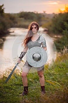 Medieval fantasy female warrior with war paint on her face, in chain mail armor, with a sword and shield in her hands