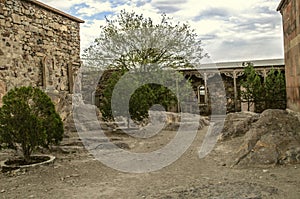 Medieval fortress of Khor Virap and a courtyard with living quarters, khachkars against the wall and trees growing among the stone