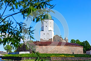Medieval fortress in Vyborg. Castle on the water against the blue sky with green foliage