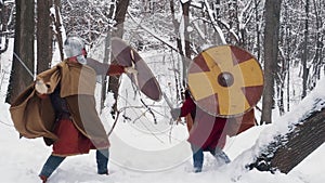 Medieval irish and frankish warriors in armor fighting in a winter forest with swords and shields