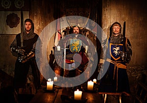 Medieval king with his knights in ancient castle interior photo