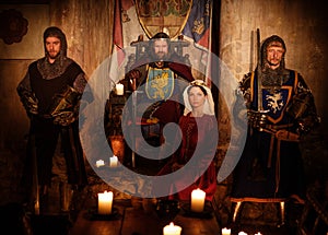 Medieval king with his queen and knights on guard in ancient castle interior