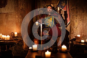 Medieval king on throne in ancient castle interior.