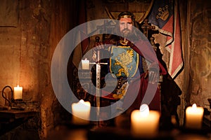 Medieval king on throne in ancient castle interior.