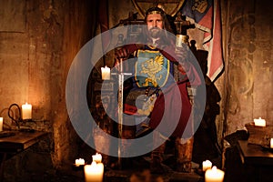 Medieval king on throne in ancient castle interior.