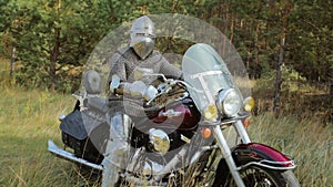 A medieval knight in full armor sits on a motorcycle against the backdrop of the forest