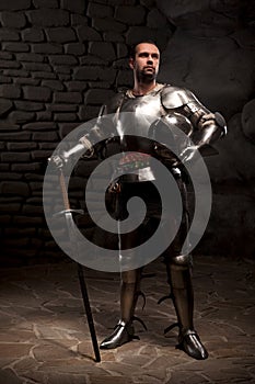 Medieval Knight posing with sword in a dark stone