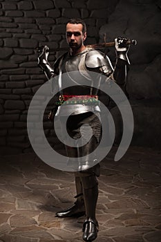 Medieval Knight posing with sword in a dark stone