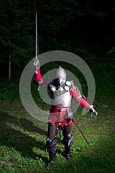 Medieval Knight With Sword in Raised Hand in the Forest at Night