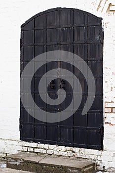 Medieval old black door with metal decoration on white