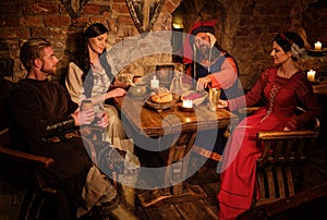 Medieval people eat and drink in ancient castle tavern