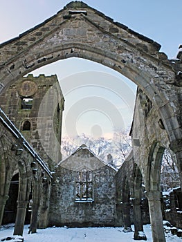 Medieval ruined church in heptonstall covered in snow showing arches and columns against a blue winter sky