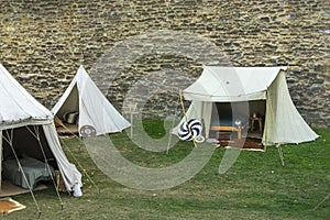 Medieval scene against the historical backdrop of an old city wall, village with tents of various designs, view of tents, village