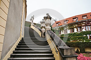 A medieval staircase in a garden or park next to the traditional houses of planted plants in Prague in the Czech