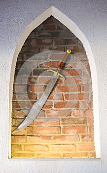Medieval steel sword against the brick wall background. Ancient shining sword used as decoration