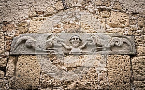 Medieval stone bas-relief depicting a man being devoured by two dragons