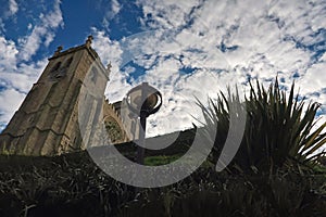 Medieval stone castle on a background of blue sky and white clouds view through the grass