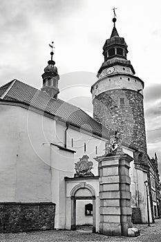 A medieval, stone church with a bell tower and a fragment of the city gate in Jelenia Gora