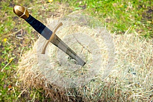 Medieval sword stuck in a pile of hay