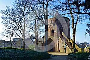 Medieval tower in sunlight surrounded by trees.