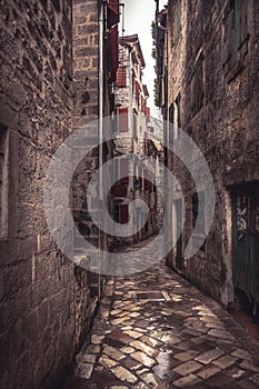 Medieval vintage narrow street with ancient stone pavers with medieval buildings in old european city Kotor in Montenegro