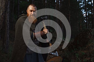 Medieval warrior viking barbarian with ax and shield in forest