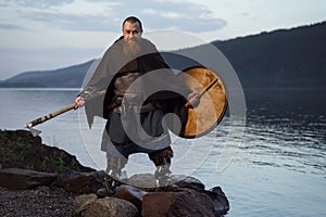 Medieval warrior viking barbarian with ax and shield on shore