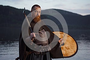 Medieval warrior viking barbarian with ax and shield on shore