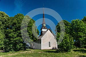 Medieval white church with tall and narrow tower and crenels photo