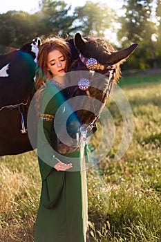 Medieval woman princess in green dress sits astride black steed horse.