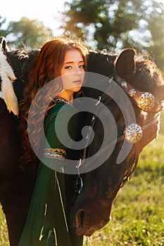 Medieval woman princess in green dress sits astride black steed horse.