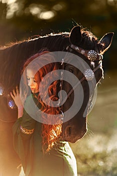 Medieval woman princess in green dress sits astride black steed horse.