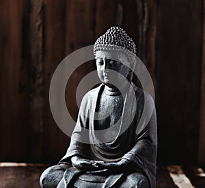 Meditating Buddha Statue on dark wooden background.