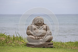 Meditating Buddha statue on tropical beach in Indonesia