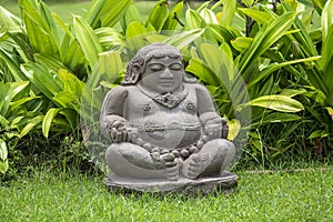 Meditating Buddha statue in tropical garden in Bali, Indonesia