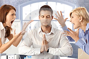 Meditating businessman with arguing colleagues photo