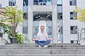 A meditating young man against the backdrop of a large business center