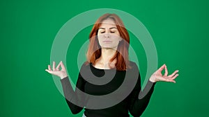 meditation folded hands close eyes on a green background attractive woman smiling bright red hair chromakey space for