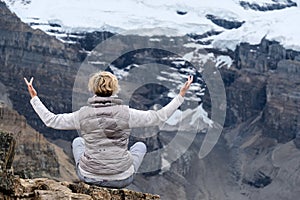 Meditation in mountains. Woman meditating on rock in front of  glaciers and snow.