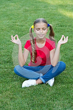 Meditation practice. Little child do meditation on green grass. Small girl sit in mudra position during meditation. Yoga